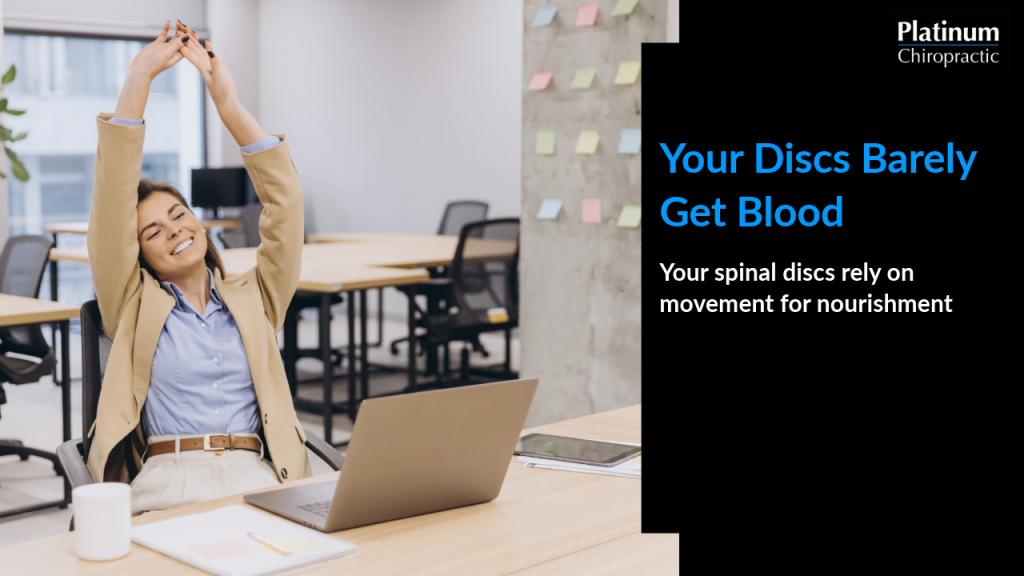 Woman stretching at her desk to support spinal disc health through movement